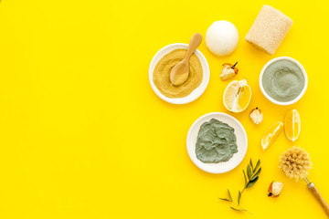 Face, body skin care homemade ingredients - cosmetic clay, brushes, homemade soap, scrub, herbs on a yellow background - top view