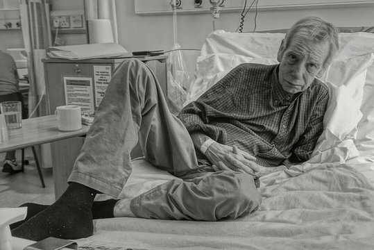 Portrait Of Senior Man Reclining On Bed At Hospital