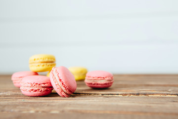 Sweet colorful French macaroon cookies dessert on brown wooden table over white wooden background