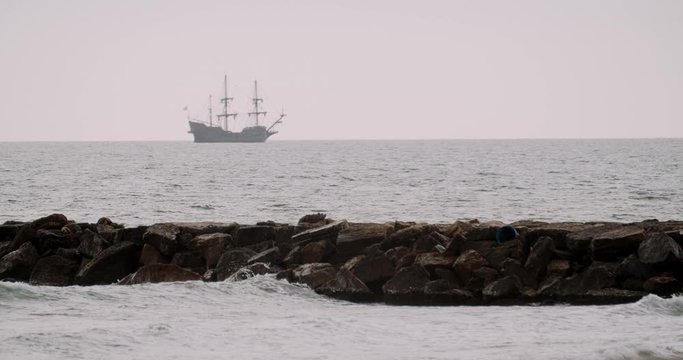 Christopher Columbus caravel replica ship sails in the mediterranean sea in Valencia with a breakwater in the foreground