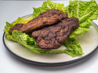 Dietary breakfast with liver patties and fresh lettuce on a light ceramic plate. Liver pancakes