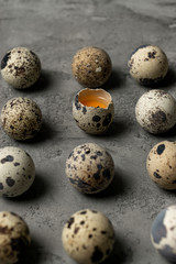 Obraz premium Many quail eggs on a concrete surface. One egg is broken and the yolk is visible.
