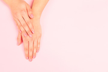 Obraz na płótnie Canvas female manicure. Beautiful young woman's hands on pastel pink background - Image