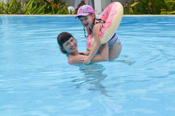 Mother and daughter have fun during the summer holidays. Happy swimming in the pool