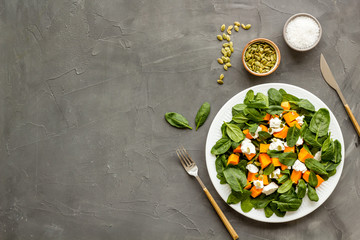 Healthy food concept. Salad with pumpkin and basil on grey background top-down copy space