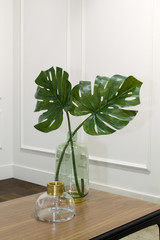 monstera leaves in a glass vase on a wooden table in an elegant interior