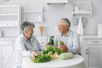Couple in a kitchen. Grandparents sitting at home. Woman with vegetables