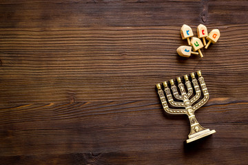 Jewish holiday Hanukkah with menorah - traditional Candelabra - and wooden dreidels spinning top. Wooden background, top view, copy space