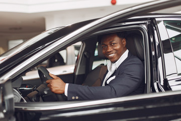 Fototapeta na wymiar Man buying the car. Businessman in a car salon. Black male in a suit.