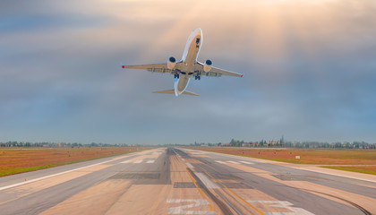 Fototapeta na wymiar White Passenger plane fly up over take-off runway from airport 