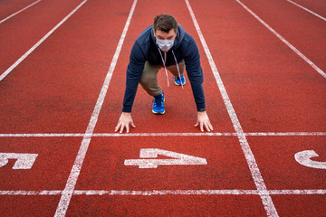 Fototapeta premium Man in surgical mask on track starting to run