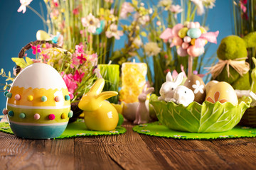 Fototapeta na wymiar Happy Easter background. Bouquet of spring flowers. Easter decorations and Easter eggs in basket on rustic wooden table.
