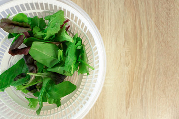 Salad and spinach leaves on wooden kitchen table with copy space, top view. Cooking dinner, lifestyle. Fresh healthy eating and vitamin food