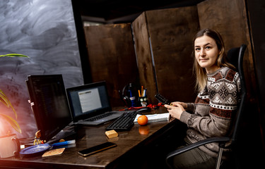 Cheerful office worker is sitting near table and looking at camera.Modern office interior. Business concept.