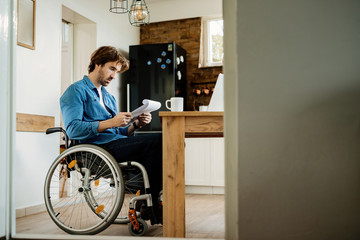 Young disabled businessman reading reports while working at home.