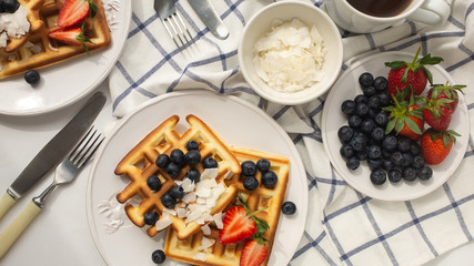 Beautiful breakfast: Viennese Belgian waffles decorated with berries, a plate with strawberries and blueberries