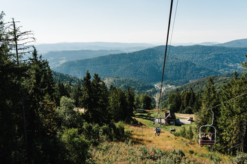Family rides on a ski lift in the mountains. Mom, dad and girl in mountains in nature. The concept of summer holiday.