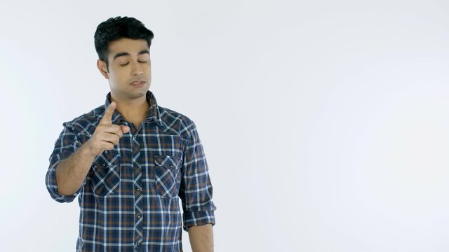 Frustrated Indian man yelling and insulting someone against the white background. Portrait of a young irritated guy in casual wear  gesturing and shouting while looking at the camera in anger - emo...