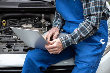 Mechanic using laptop for checking car engine