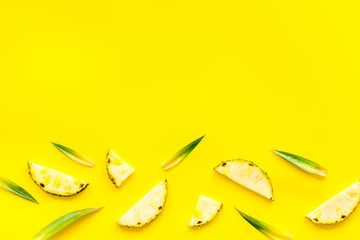 Pineapple slices on yellow background top-down frame copy space