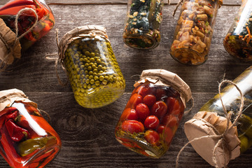 top view of homemade tasty pickles in jars on wooden table
