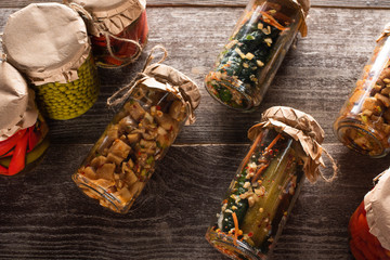 top view of homemade tasty pickles in jars on wooden table