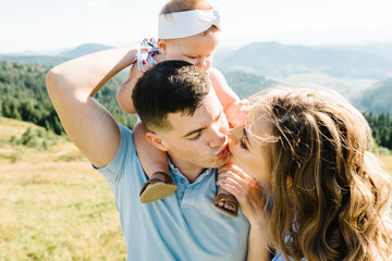 Portrait of happy family. Mom, dad hugging daughter at nature. Young couple spending time together on vacation, outdoors. The concept of summer holiday. Mother's, father's, baby's day.