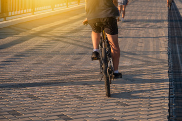 A man in shorts rides a bicycle on a bright sunny day on the paving stones on the promenade