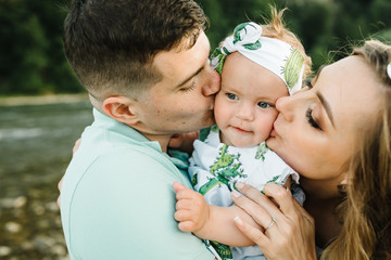 Mom, dad and daughter hugging, enjoy and walking at nature. Young family spending time together on vacation, outdoors. The concept of family summer holiday.