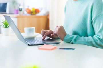 Close up of female browsing through internet sites, scrolling on her laptop.