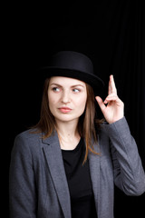 cute young girl in hat and gray jacket on black background