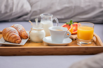 Breakfast in bed with  orange fruits and pastries on a tray