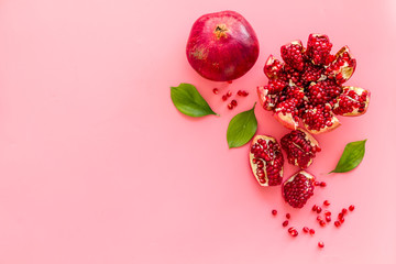 Ripe pomegranate fruit near leaf on pink background top-down copy space