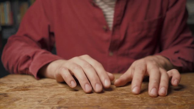 Young man tapping his fingers on wooden table