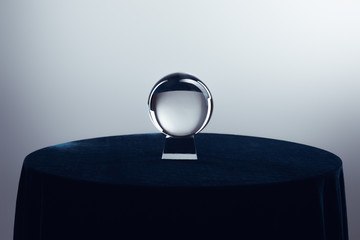 Crystal ball on round table on grey background