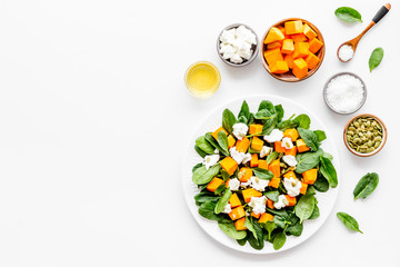 Salad with pumpkin and basil - near ingredients - on white background top-down copy space