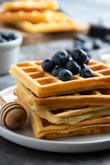Stack of belgian waffles with blueberry and honey for breakfast. Delicious homemade pastry. Copy space.