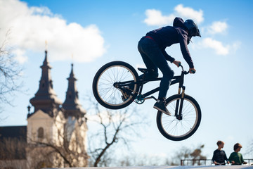 Young man doing tricks on a BMX bike. BMX freestyle against the backdrop of urban landscape. Extreme sports is very popular among youth.