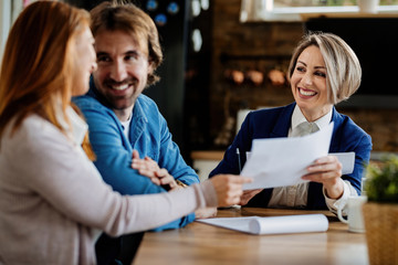 Happy real estate agent having a meeting with young couple.