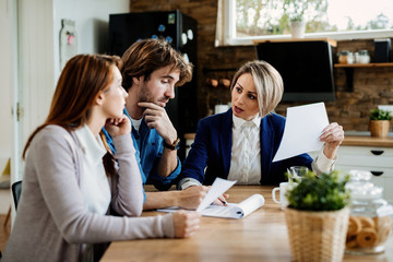 Insurance agent talking to a couple about terms of their lease agreement during a meeting.