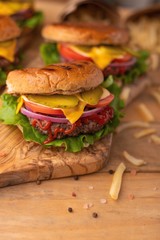 Home or restaurant cuisine. Two fresh large hamburgers with french fries on a wooden background. Vertical photo. Cafe and eateries, restaurant food.