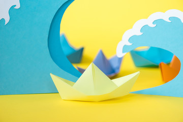 selective focus of paper ship near waves on yellow