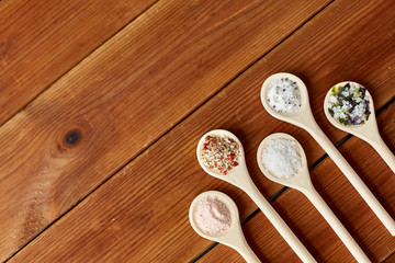 Obraz na płótnie Canvas food, culinary and unhealthy eating concept - spoons with salt and spices on wooden table