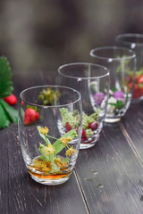 Fototapeta na wymiar set for making medicinal tea in transparent glass glasses with medicinal herbs and fruits-Linden, cherry, strawberry, clover