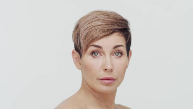 Close-up of middle aged mature woman over white bacjground. Portrait of mature lady. Plastic surgery, beauty injections and cosmetology.