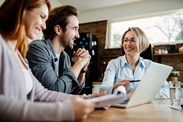 Below view of happy financial advisor talking to a couple during the meeting.