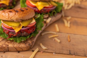 Burgers on a wooden background with french fries, with space for design