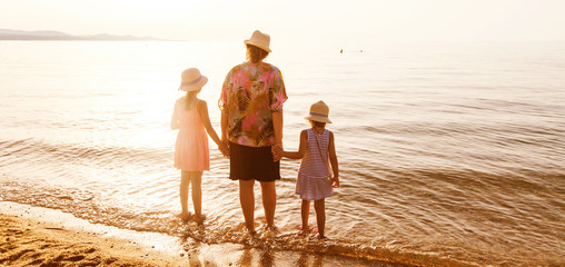 Rearview of family relax on sand beach at sunset during summer v