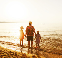 Rearview of family relax on sand beach at sunset during summer v