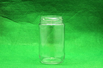 Glass empty bottle on green background, side view.